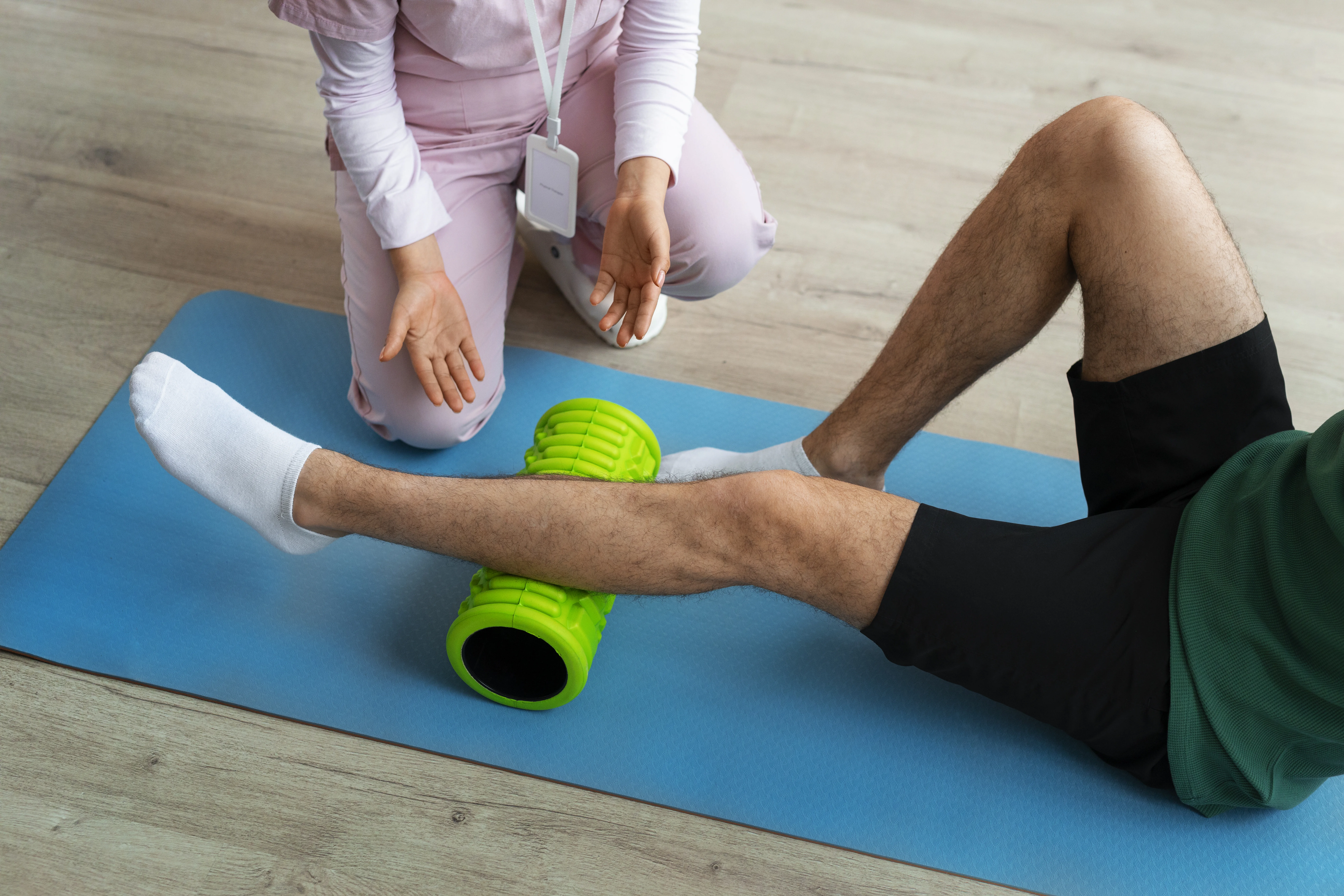 physiotherapist exercising patient leg with a roller, bellow the leg
