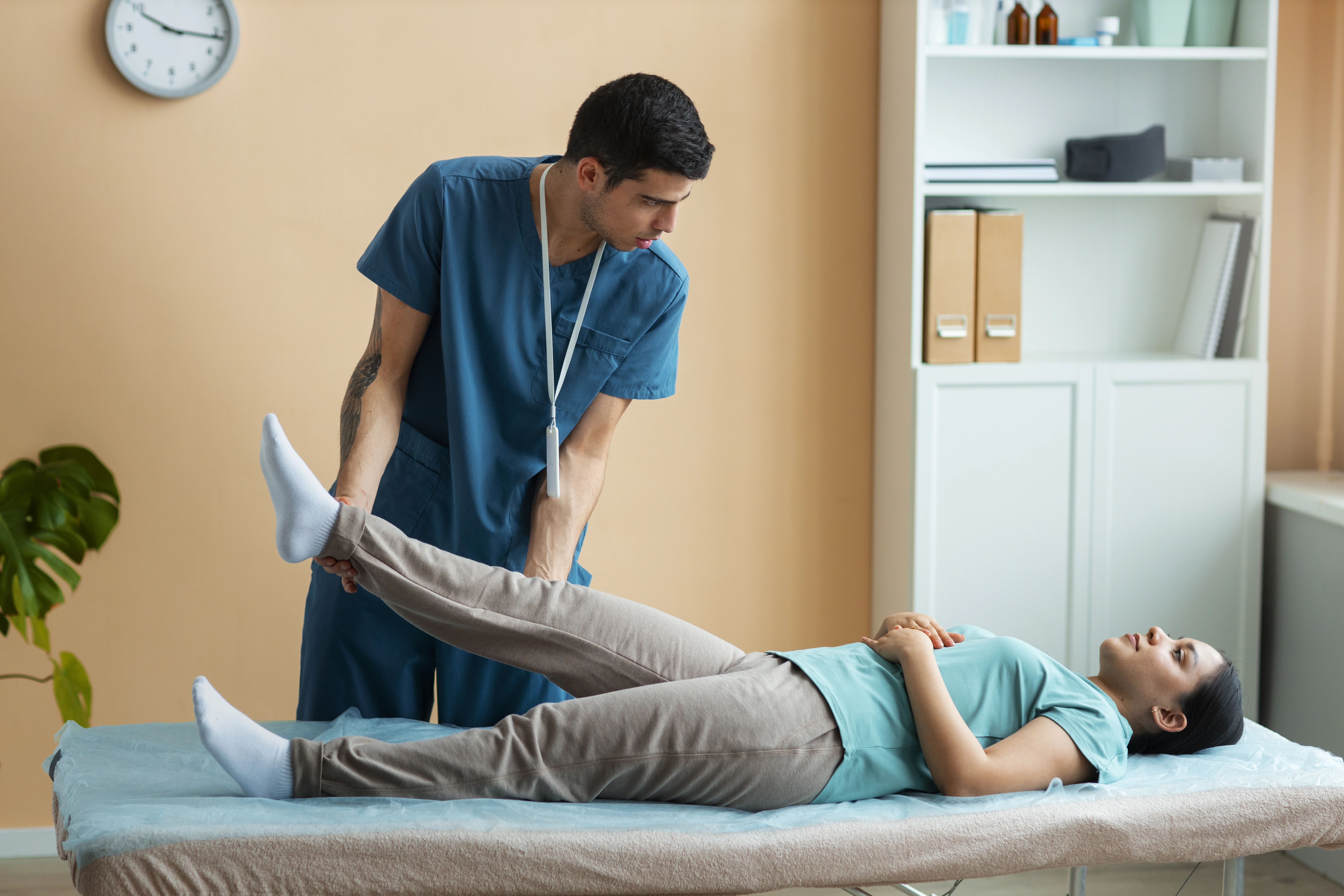 Physiotherapist assisting a woman with leg stretching exercise on a treatment table
